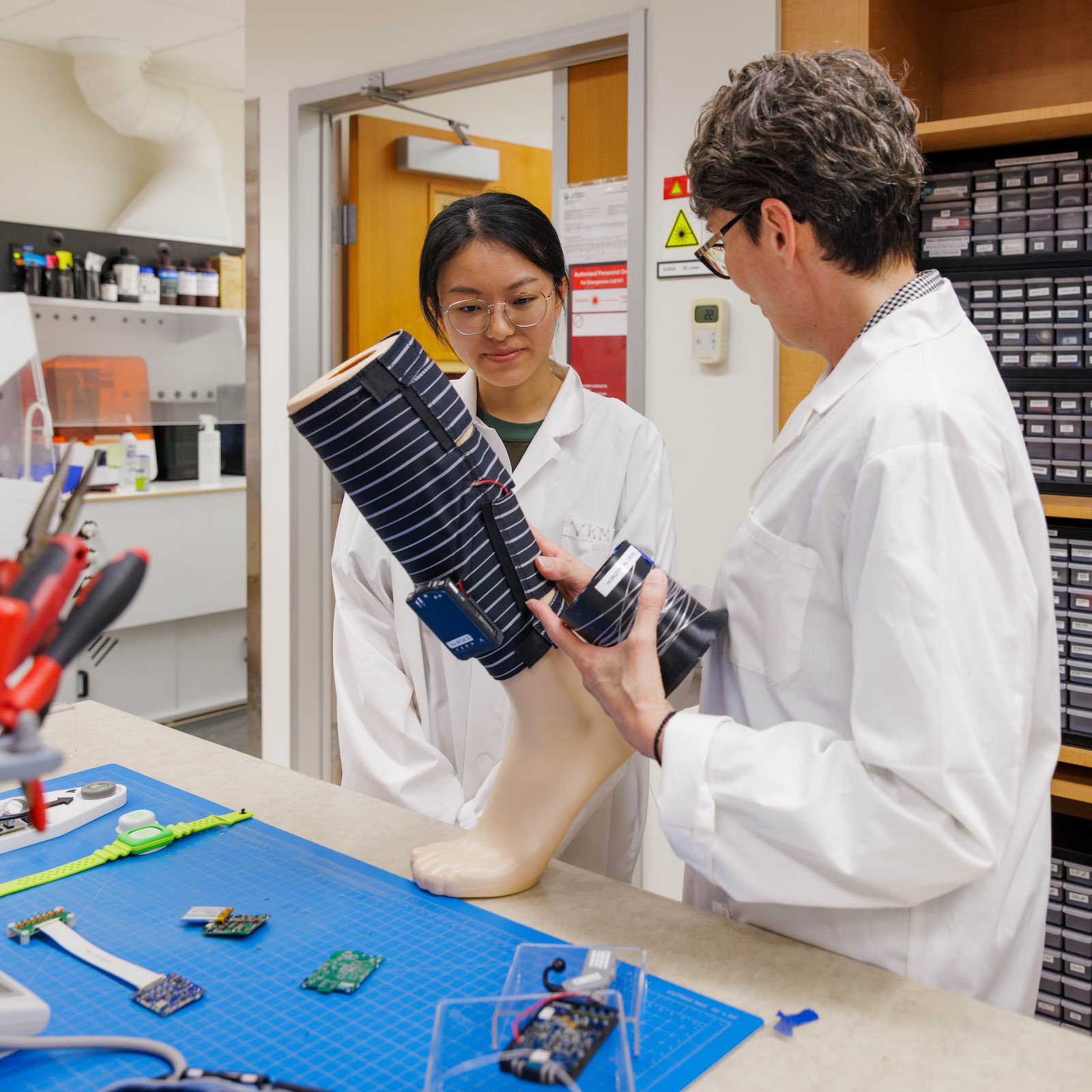 Vivian Mushahwar and a student examine a mannequin foot wearing smart leg wraps